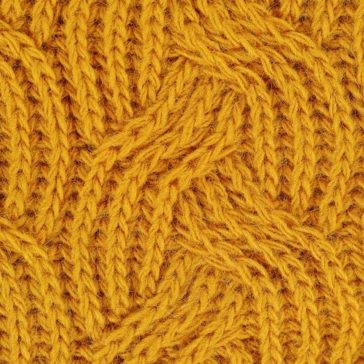 Detailed close-up of a yellow knitted wool pattern, ideal for textile design.
